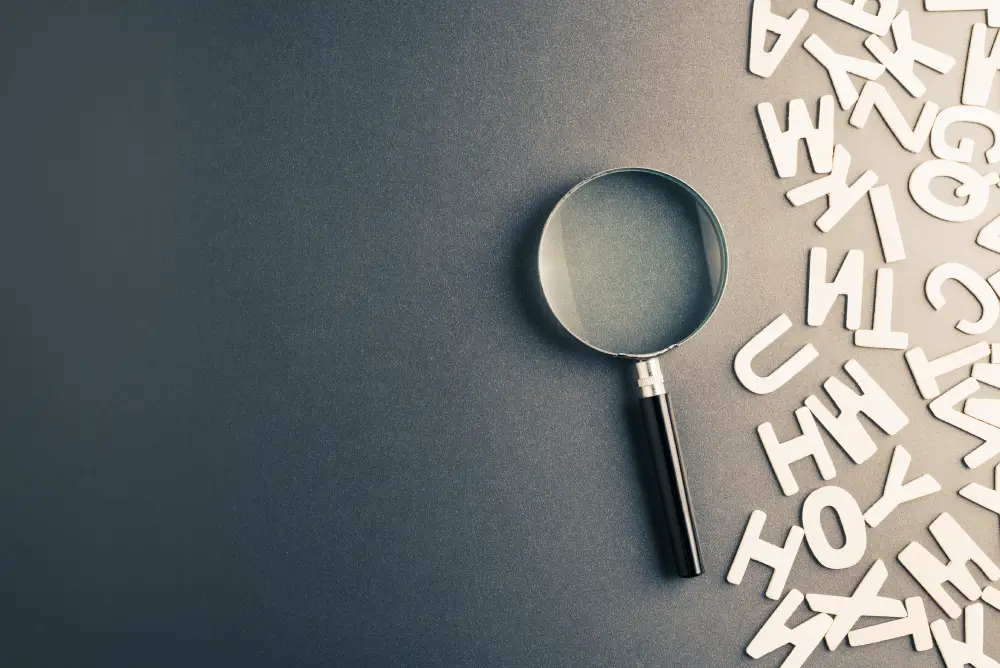 magnifying glass on a table next to a pile of white letter