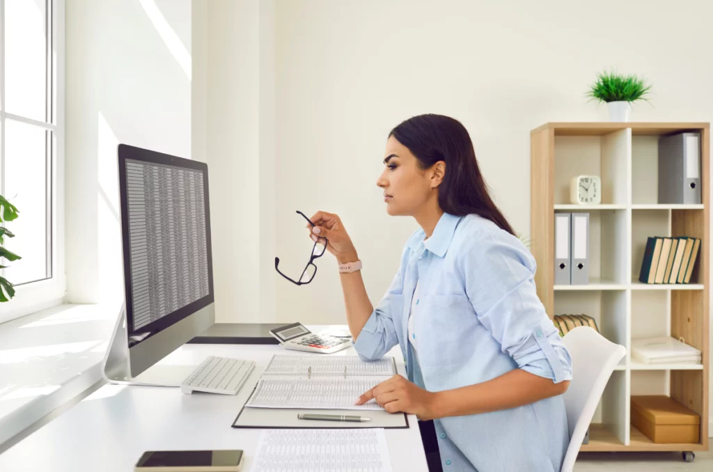 woman looks at data tables on a computer at home