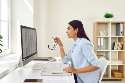 woman looks at data tables on a computer at home